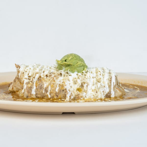 A Juan Great Fiesta burrito, smothered in green sauce, shredded cheese, sour cream, and guacamole.